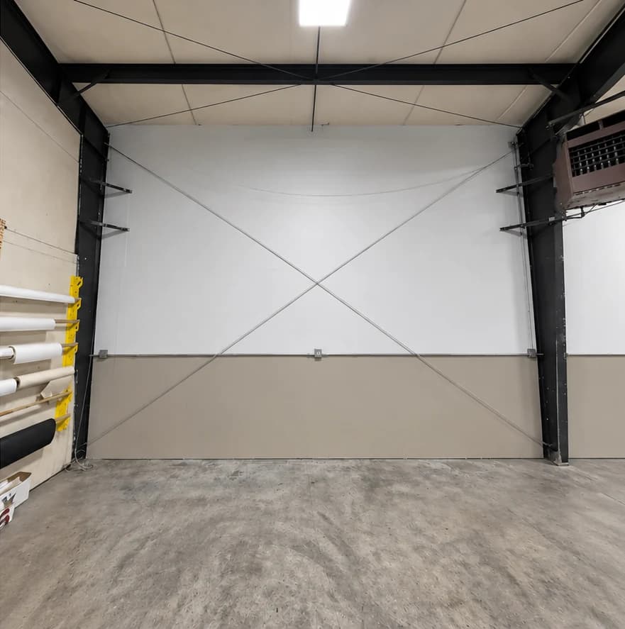 After repainting: commercial wall with a white upper section and taupe lower section, framed by black steel beams.