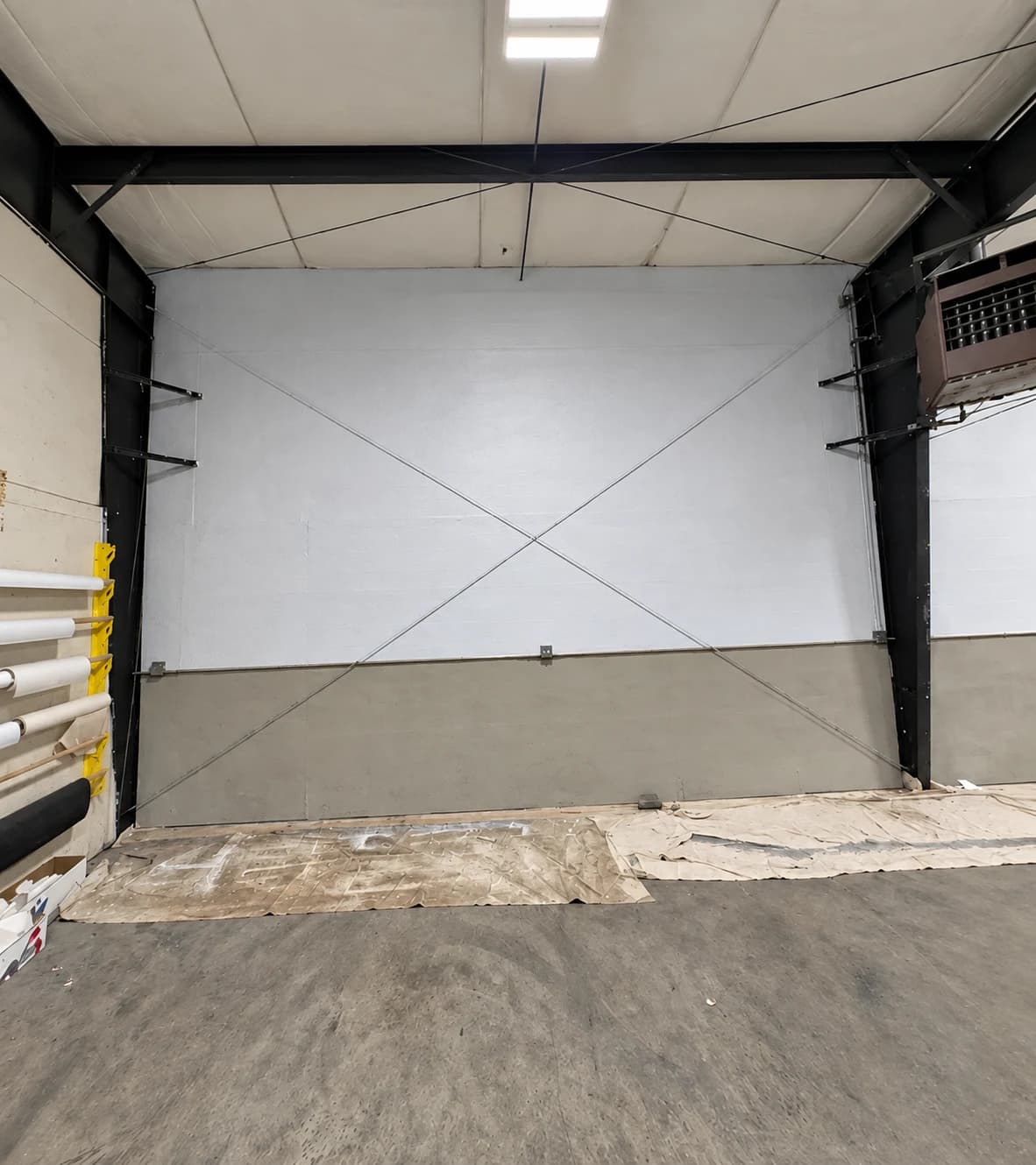 After repainting: commercial wall with a white upper section and taupe lower section, framed by black steel beams.