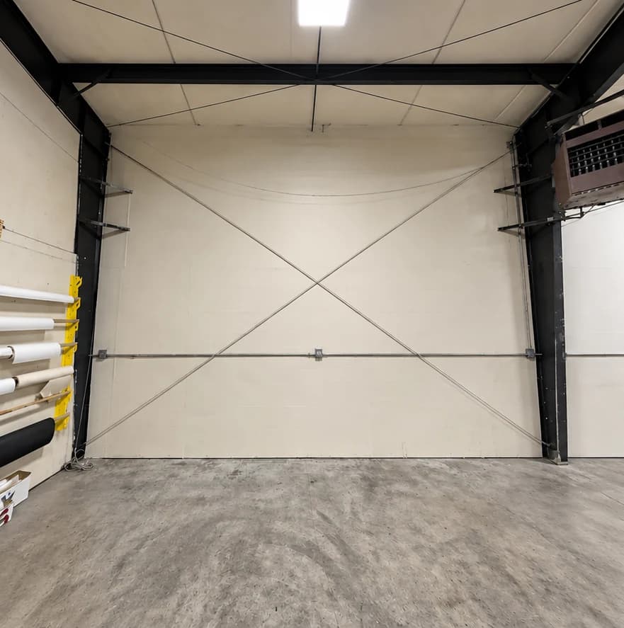 Before repainting: cream-colored commercial wall with exposed diagonal metal bracing and black steel beams.