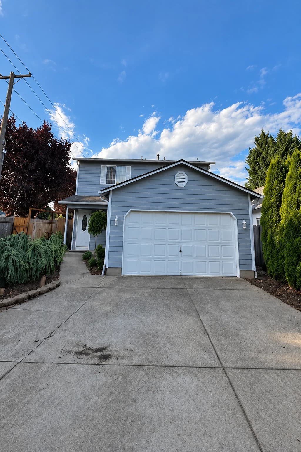 After exterior painting: two-story Vancouver home with blue-gray lap siding, white trim and a white garage door.